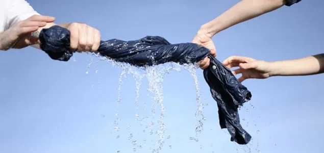 Two people wringing water out of a pair of jeans